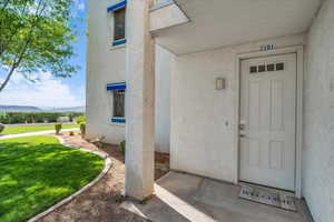 Entrance to property with stucco siding, a yard, and a mountain view