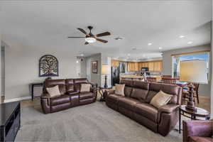 Living area with recessed lighting, light colored carpet, and a ceiling fan