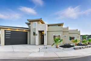 Contemporary house featuring stucco siding, stone siding, an attached 3 car garage, and concrete driveway and easy-care land scaping.