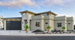 View of front of house with stucco siding, stone siding, a garage, and driveway