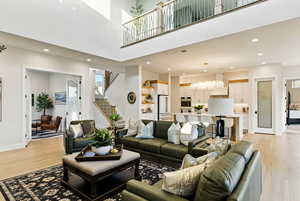 Living room with recessed lighting, light wood-style floors, and a high ceiling