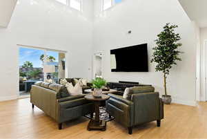 Living room with plenty of natural light, light wood-type flooring, and a towering ceiling