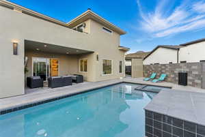 View of pool with a patio area, an outdoor living space, and a pool with connected hot tub. There is an outdoor shower tucked around the corner.