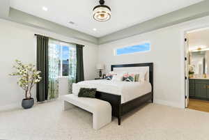 Bedroom featuring multiple windows, connected bathroom for loads of light, light colored carpet, a raised ceiling, and recessed lighting