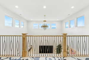 Hall featuring recessed lighting, healthy amount of natural light, and a chandelier with Juliet style inner balcony and with large glass sliding doors.
