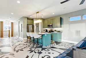 Kitchen featuring recessed lighting, a breakfast bar area, appliances with stainless steel finishes, a center island with sink, and decorative light fixtures