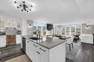 Kitchen featuring open floor plan, glass insert cabinets, white cabinetry, light stone countertops, and a wall of windows