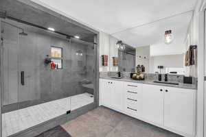 Bathroom featuring double vanity, a shower stall, and light tile patterned floors