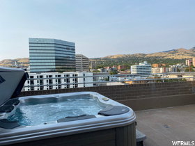 View of patio / terrace with a view of city, a hot tub, and a mountain view