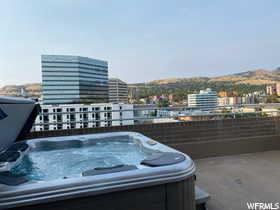 View of patio / terrace with a view of city, a hot tub, and a mountain view