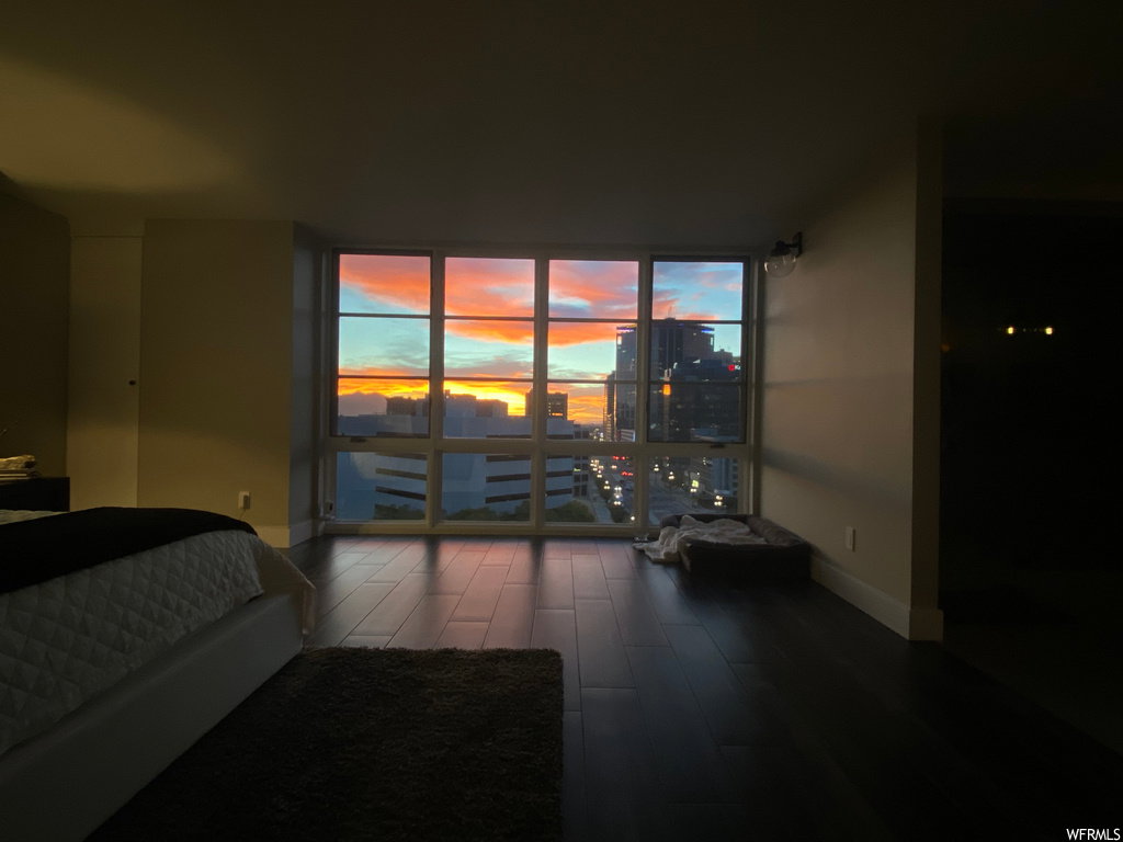 Bedroom featuring dark wood-style flooring, a city view, and floor to ceiling windows