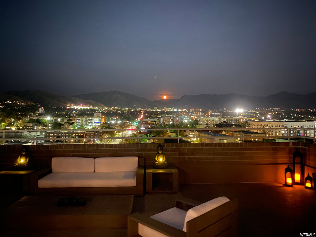 Patio at twilight featuring a patio area, a mountain view, and a view of city lights