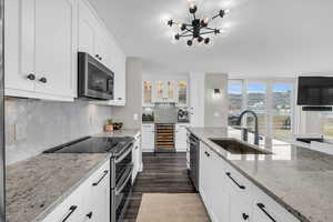 Kitchen featuring stainless steel appliances, beverage cooler, white cabinetry, glass insert cabinets, and floor to ceiling windows