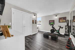 Exercise room with dark wood-type flooring and baseboards