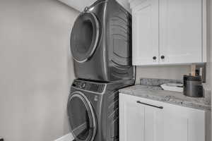 Laundry room featuring estacked washer and dryer and cabinet space