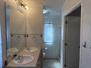 Bathroom with crown molding, a shower stall, and double vanity