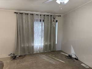 Carpeted spare room with ornamental molding and a ceiling fan