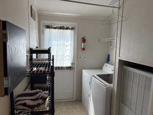 Washroom featuring a heating unit, separate washer and dryer, and light tile patterned flooring