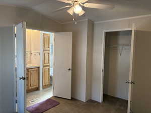 Unfurnished bedroom with carpet floors, crown molding, ceiling fan, a closet, and vaulted ceiling