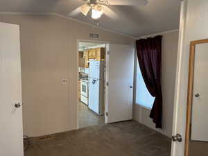 Empty room with crown molding, a ceiling fan, lofted ceiling, and dark carpet
