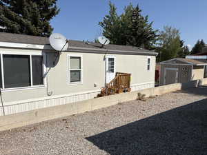 Rear view of property with a storage shed and a shingled roof