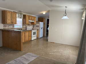 Kitchen featuring backsplash, white electric range oven, tile counters, hanging light fixtures, and vaulted ceiling