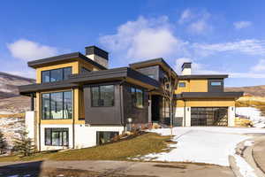 Contemporary home with a chimney, a garage, driveway, and a mountain view