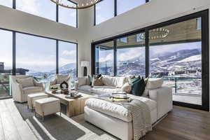 Living area with a mountain view, hardwood / wood-style flooring, a chandelier, and a high ceiling
