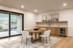 Dining room featuring wine cooler, light wood-type flooring, and recessed lighting