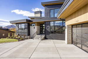 View of exterior entry with stone siding, a chimney, and a mountain view