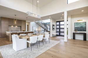 Dining room with stairway, light wood-style flooring, a high ceiling, and recessed lighting