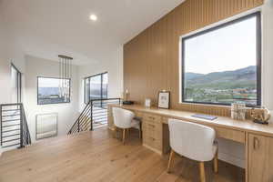 Office area featuring built in desk, wooden walls, light wood finished floors, recessed lighting, and an accent wall