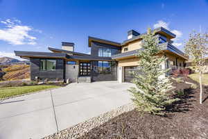 Contemporary house with a chimney, driveway, and an attached garage