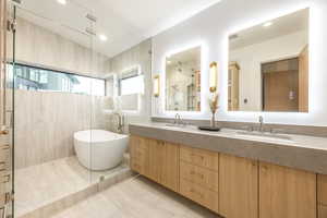Full bathroom with double vanity, a soaking tub, a tile shower, and light tile patterned floors