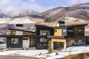 Contemporary home featuring a chimney, stone siding, and a mountain view
