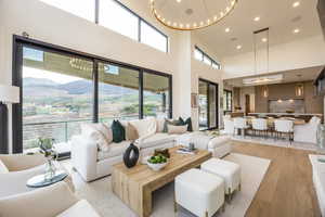 Living room featuring recessed lighting, a chandelier, light wood-style floors, a mountain view, and a high ceiling