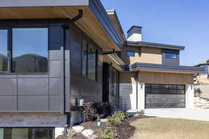 View of front facade with an attached garage, driveway, and a chimney