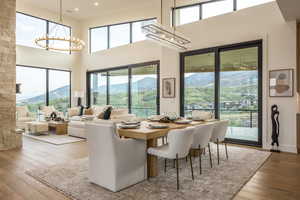 Dining space featuring a chandelier, light wood-style flooring, healthy amount of natural light, and a towering ceiling