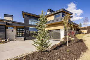 Modern home featuring a chimney, a garage, and driveway