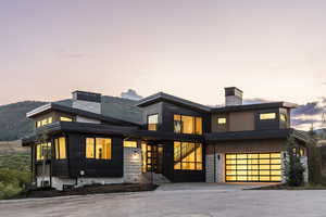 Modern home featuring a chimney, stone siding, and an attached garage