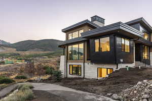 View of side of home featuring a chimney, a sunroom, and a mountain view