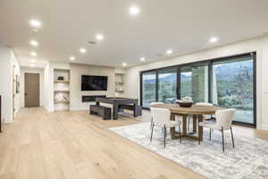 Dining room with light wood finished floors, built in features, and recessed lighting