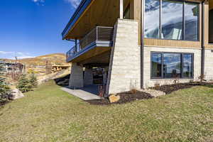 View of side of home with a yard, a balcony, a patio, and a mountain view