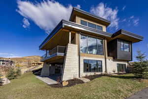 Back of house with a yard and a balcony