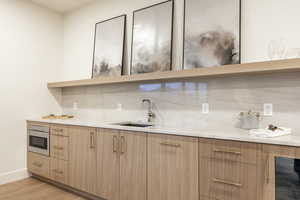 Kitchen with decorative backsplash, modern cabinets, light brown cabinets, and light stone countertops