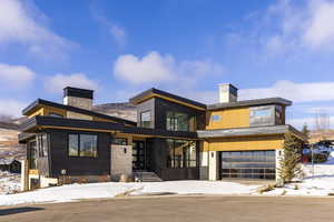 Contemporary house with a chimney, a garage, and stone siding