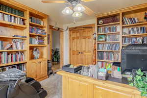 Office area with a ceiling fan and light carpet