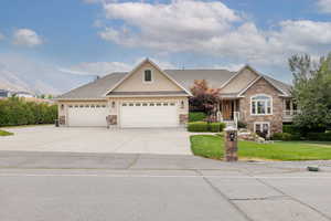 Craftsman house with a front yard, driveway, stucco siding, a shingled roof, and stone siding