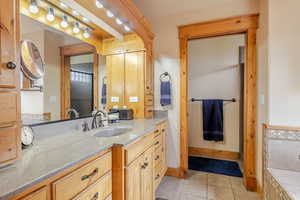 Full bathroom with light tile patterned floors, vanity, and a garden tub