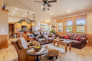 Living room featuring wainscoting, wooden walls, lofted ceiling, recessed lighting, and light wood-type flooring